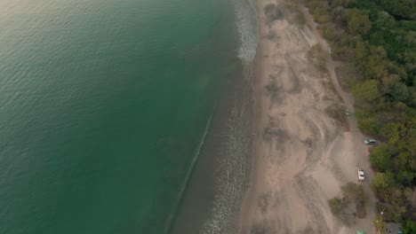 inclinación aérea revelada de autos estacionados en la playa costarricense durante la puesta de sol