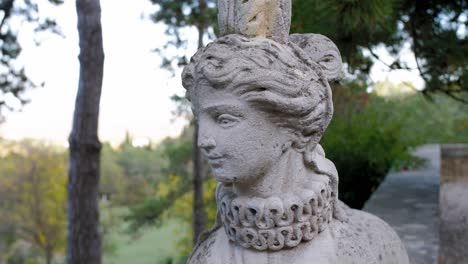 a-stone-statue-of-a-lady,-in-a-garden-with-gravel