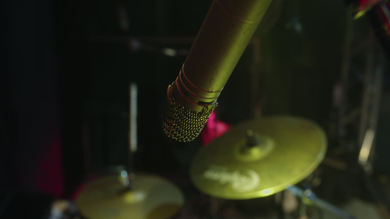 Beautiful close-up slow motion shot of a drum microphone recording during a sound check on an empty stage with yellow lights.