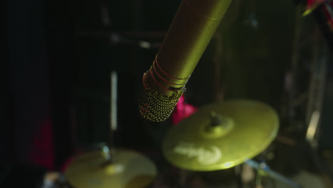 beautiful close-up slow motion shot of a drum microphone recording during a sound check on an empty stage with yellow lights.