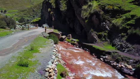 aerial, drone shot of a road and a bridge, at the pukamayu red river, on a sunny day, in cusco, peru, south america