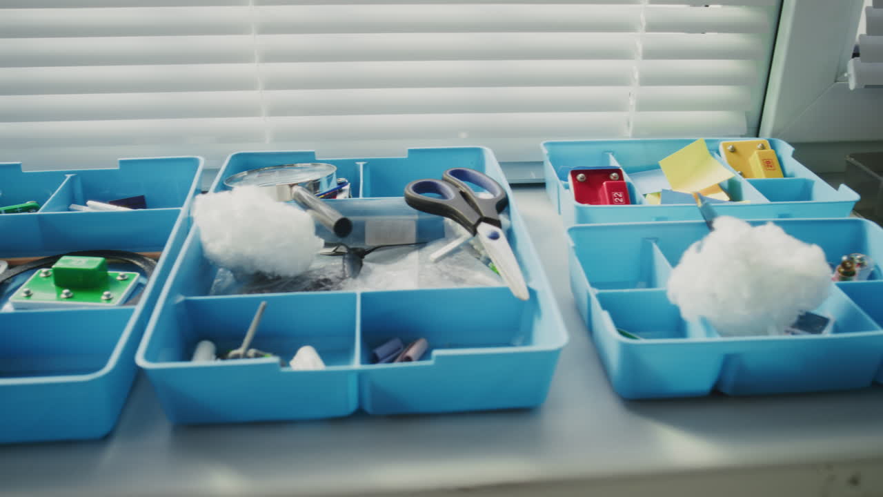 Close Up of STEM Building Set and Plasticine Lying in Plastic Boxes in Modern Classroom