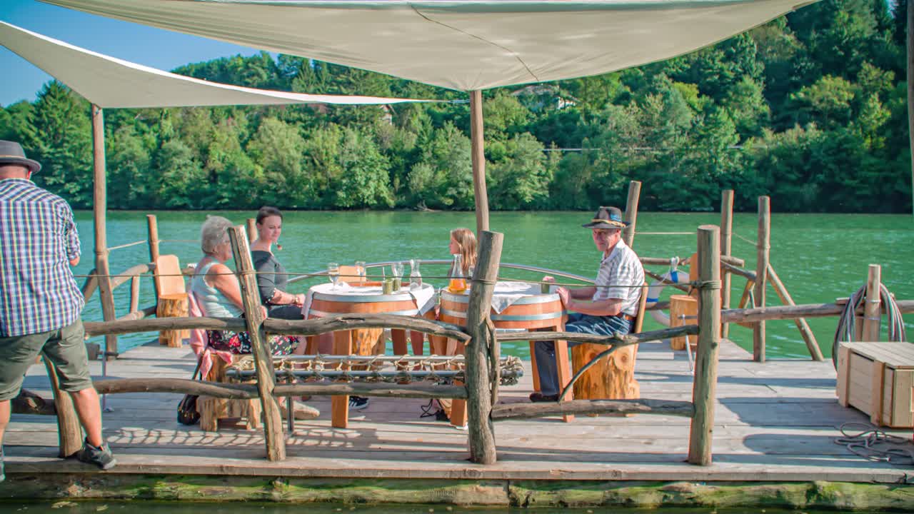 Slow motion shot of a family having a drink while navigating on a Slovenian raft on Drava river