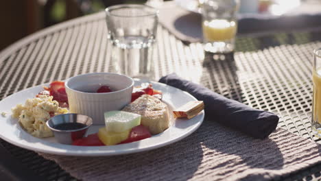 Pan-over-a-colourful-breakfast-plate,-outside-table-in-sunlight