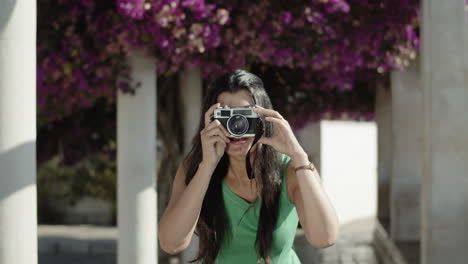 front view of young hispanic woman taking photo with camera.