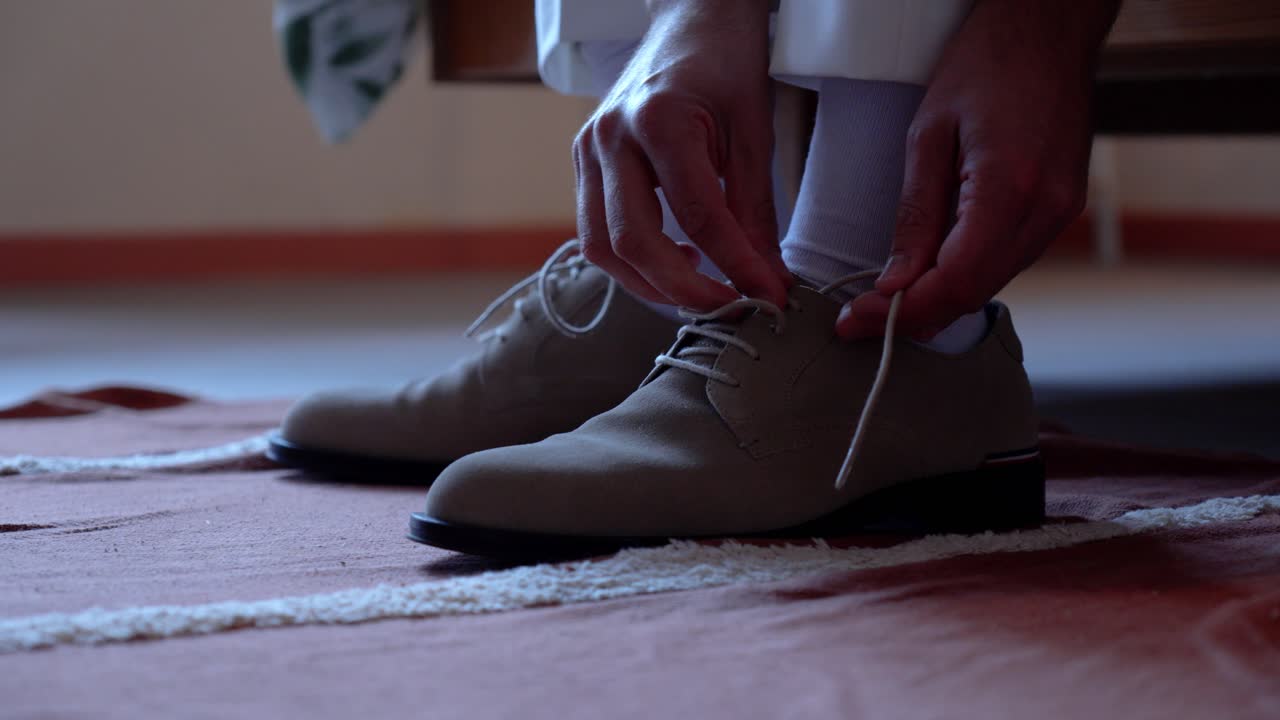 Man Tying His Beige Suede Shoelaces
