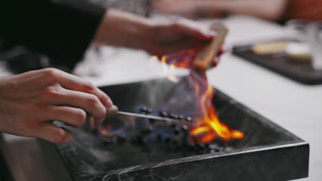 A-professional-barista-roasting-coffee-traditionally-by-hand-with-fire-on-a-granite-plate-using-BBQ-tuners