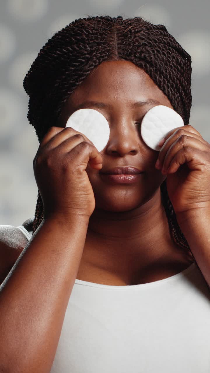 Vertical video: African american girl using cotton pads on camera