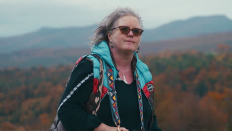 Older-fat-woman-Photographer-taking-pictures-with-her-camera-and-walking-in-autumn-nature-surrounded-by-colourful-trees-during-a-cold-windy-day-in-slow-motion