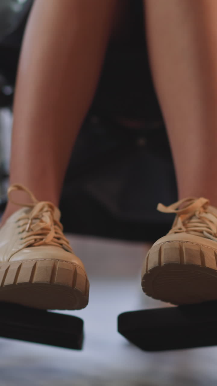 척추 마비를 고 체어에 앉아있는 젊은 여성의 다리가 흐릿한 배경에서 보살하는 여성 환자가 근접으로 움직일 수 있도록 도와줍니다.