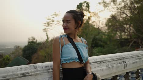 smiling asian woman with flower in hair at outdoor viewpoint