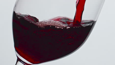 closeup pouring red wine glass indoors. alcoholic liquid filling wineglass