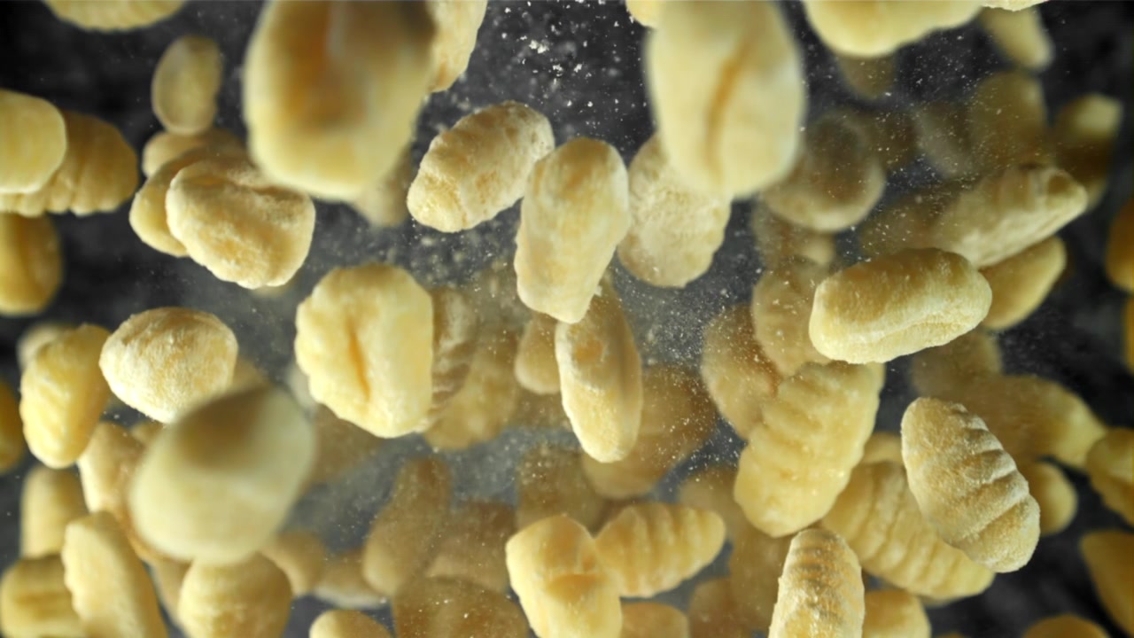 Gnocchi crudi che cadono al rallentatore con polvere di farina