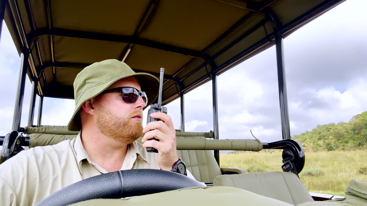 Game ranger communicates by radio from safari vehicle in African wilderness