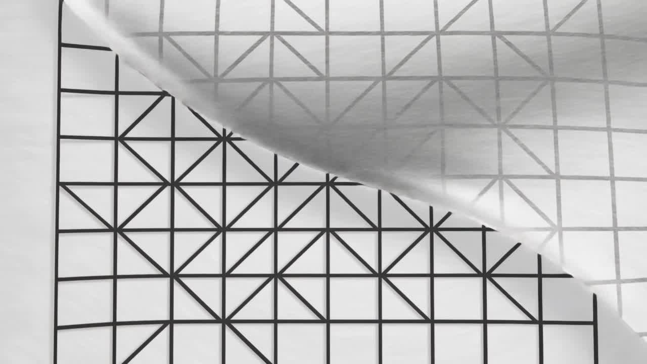 Corner lifting starting clear film sliding across grid paper with bold lines on white surface