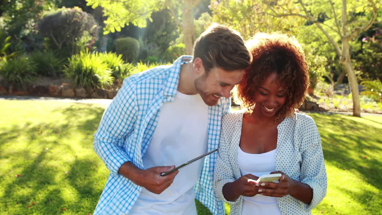 pareja feliz usando tableta digital y teléfono móvil