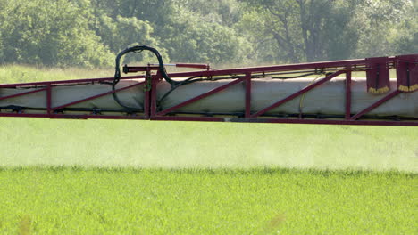 telephoto shot of hazardous pesticide crop spraying from boom sprayer on tractor