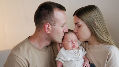 caring and loving parent kiss their sleeping baby on the head. beautiful family of three portrait.