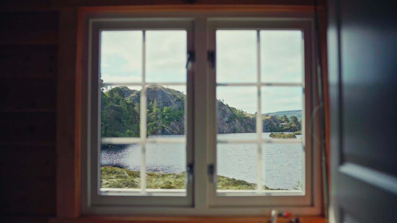 A Serene Cabin Window in Bessaker Offers a View of a Calm Lake, Surrounded by Rocky Hills and Greenery, in Åfjord Municipality, Trøndelag, Norway - Close Up