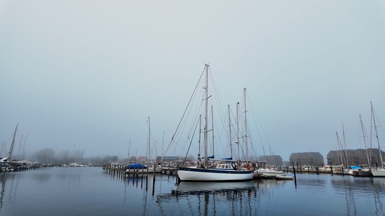 On a cloudy day, yachts with their masts outstretched stand still in a small pleasure boat harbor. Scandinavia Denmark.
