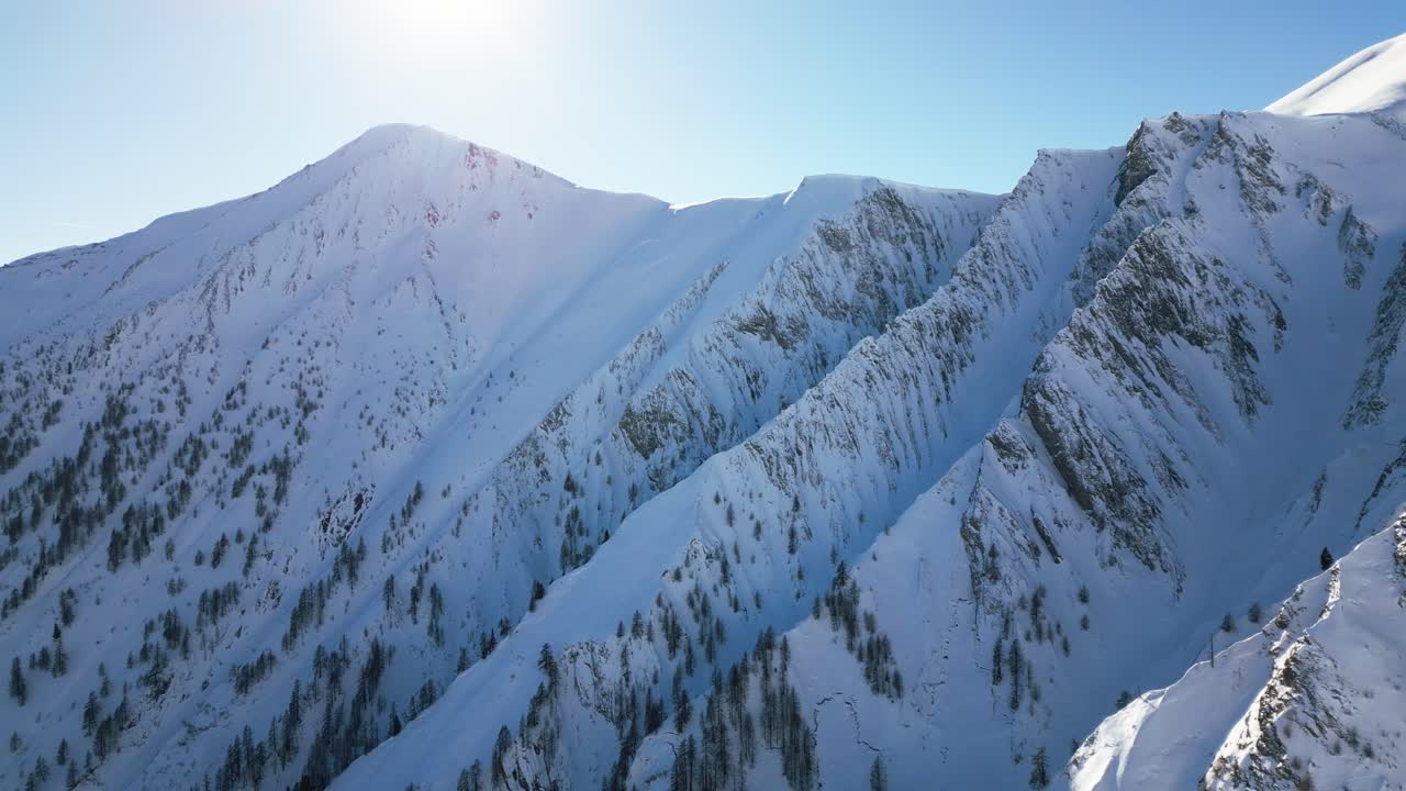 die kamera fliegt entlang schöner schneebedeckter weißer berge mit einem blauen himmel und der leuchtenden sonne