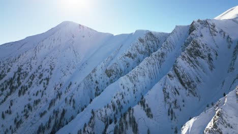 the-camera-flies-along-beautiful-snow-covered-white-mountains-with-a-blue-sky-and-the-sun-shining