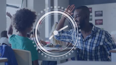 Animation-of-clock-over-african-american-male-teacher-high-fiving-with-schoolboy-at-desk-in-class