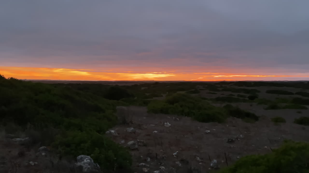 Golden sunset light spills across the Algarve hills, blending sky and earth in serene balance