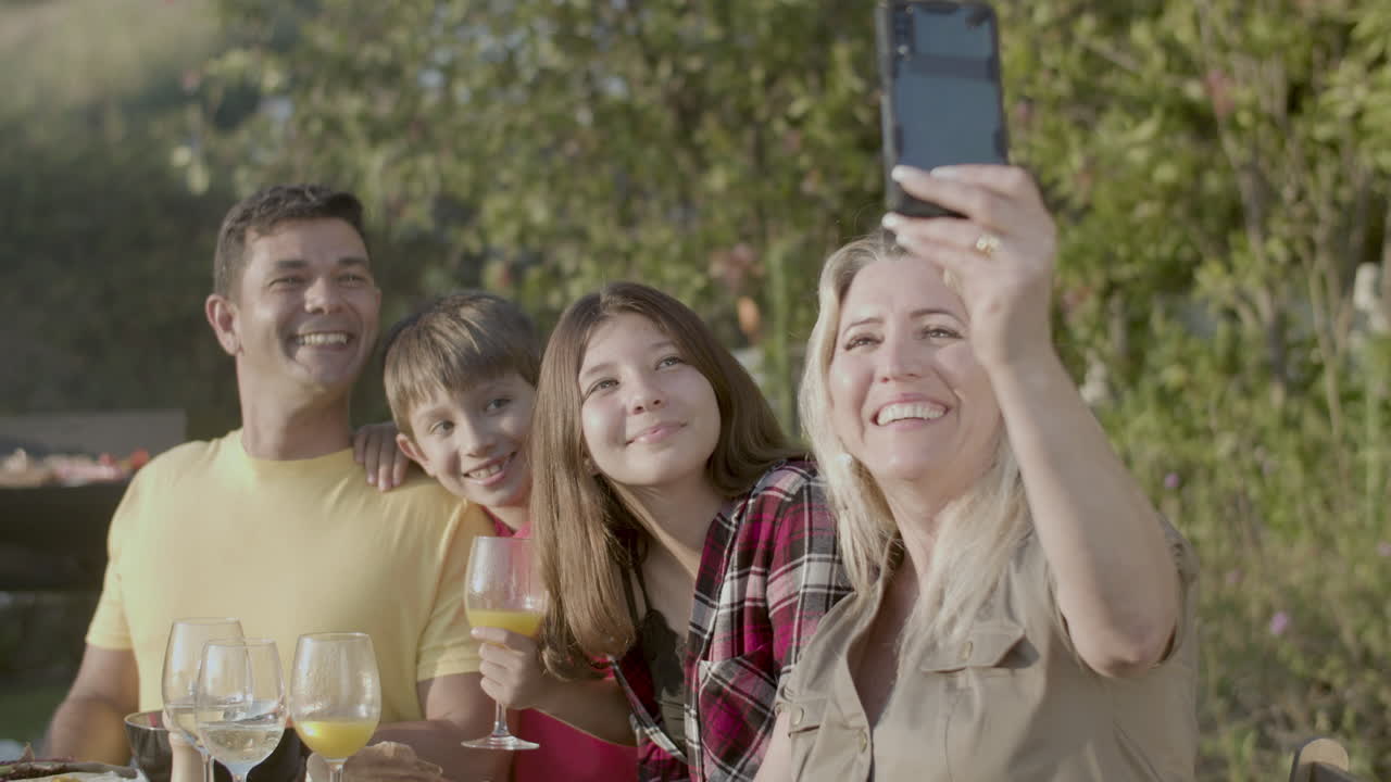 mujer feliz tomando una selfie de su familia en una fiesta de jardín
