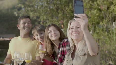 happy woman taking selfie of her family at garden party