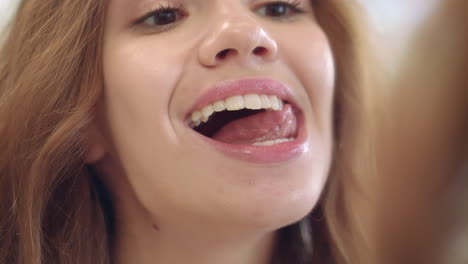 Happy woman licking white teeth with tongue