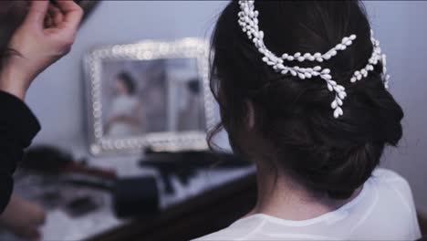 bridesmiaid decorando el cabello de la novia con una diadema blanca