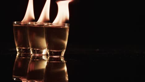 Video-of-lit-alcohol-in-glasses-with-yellow-fire-flames-and-copy-space-on-black-background