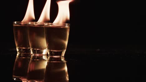 video of lit alcohol in glasses with yellow fire flames and copy space on black background