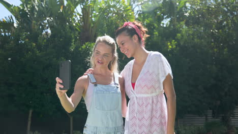 two female friends outdoors sharing excitement while looking at smartphone together