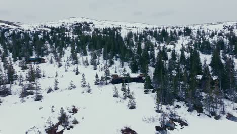 Flying-Towards-Wooden-Cabin-On-Snow-covered-Mountain-In-Verran,-Norway