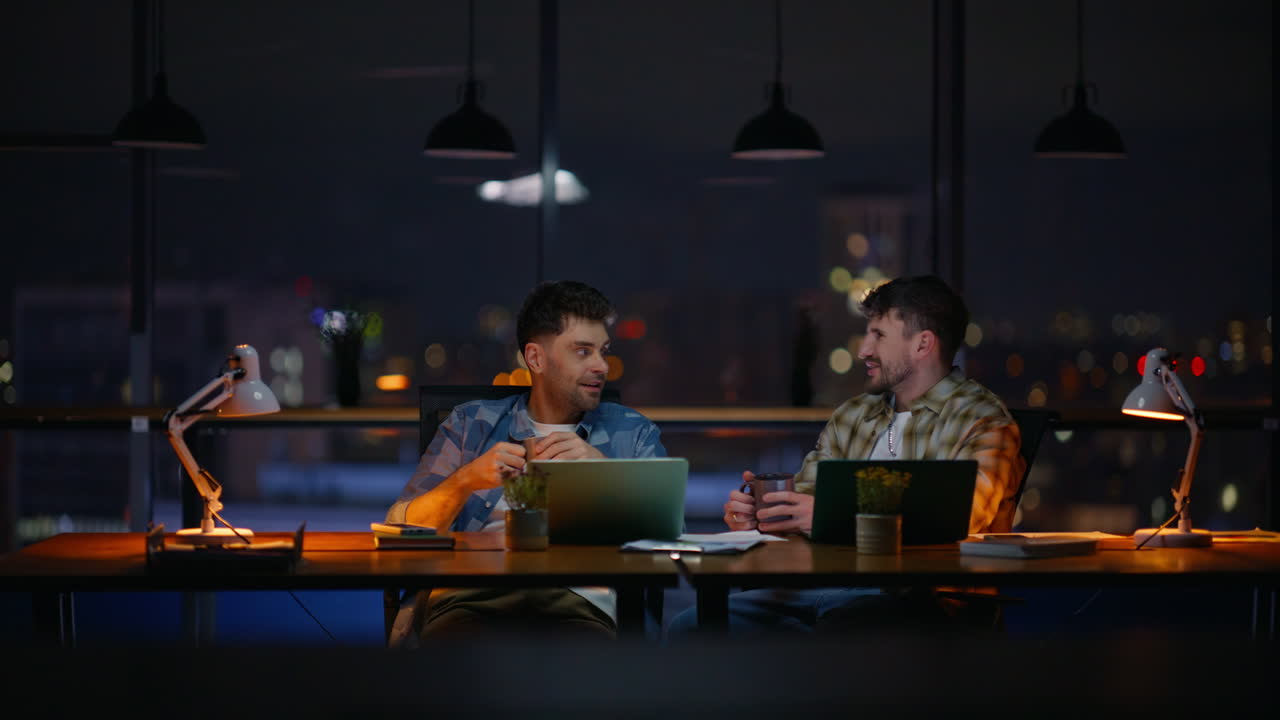 Relaxed men talking office sipping tea together. Positive guys taking break