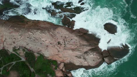 Topdown-view-of-Famous-Pedra-do-Arpoador,-rocky-peninsula-with-ocean-waves-crashing,-Rio-de-Janeiro