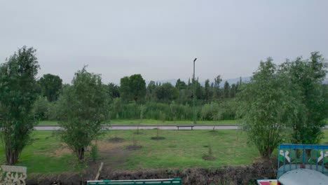 Pull-left to right above a lake, with view of a trail and a runner, in natural area in Mexico City, with view of some trees