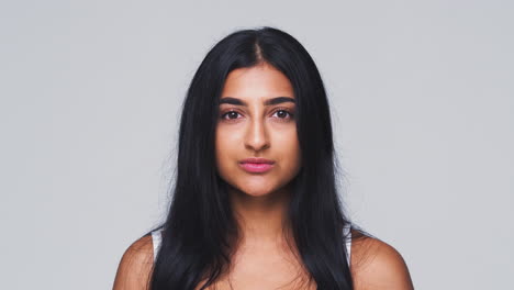 head and shoulders studio shot of woman looking at camera with serious expression in slow motion