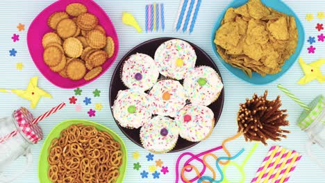 pasteles para la fiesta de cumpleaños se mueven en círculo en la mesa con la comida de la fiesta y las decoraciones - detenga el movimiento