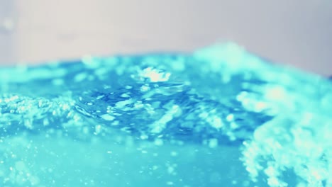 The-clean-water-surface-in-slow-motion-fills-the-screen-with-water-splashing-shop-the-water-drop-and-waving-liquid-surface-with-an-air-bubble