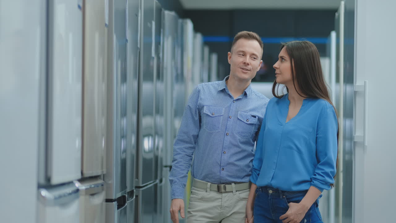 Buying a new refrigerator. Choosing the right model for a family couple in an electronics store.