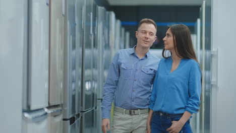 comprar un refrigerador nuevo. elegir el modelo adecuado para una pareja en una tienda de electrónica.