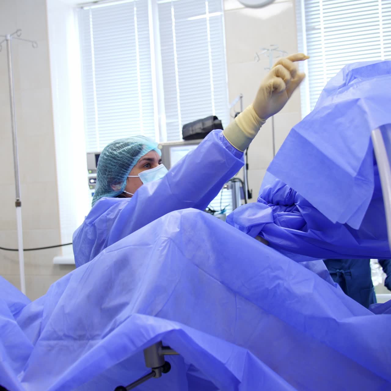 Surgical assistant is covering the equipment with blue sheets. Getting ready for the operational procedure