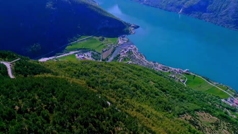 high angle shot of beautiful norwegian fjord with the view of a town along the shore surrounded by mountain range on a sunny day