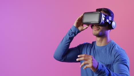 Video-of-smiling-biracial-man-using-vr-headset,-with-copy-space-on-pink-background