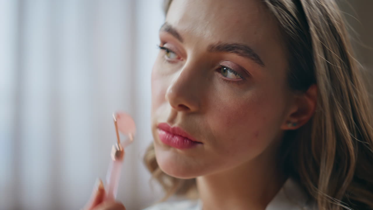 mujer usando un rodillo de jade para masaje facial