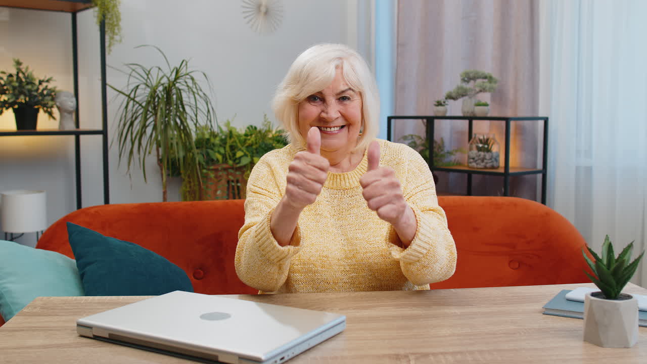 Happy senior old woman looking approvingly at camera showing thumbs up like positive sign good news