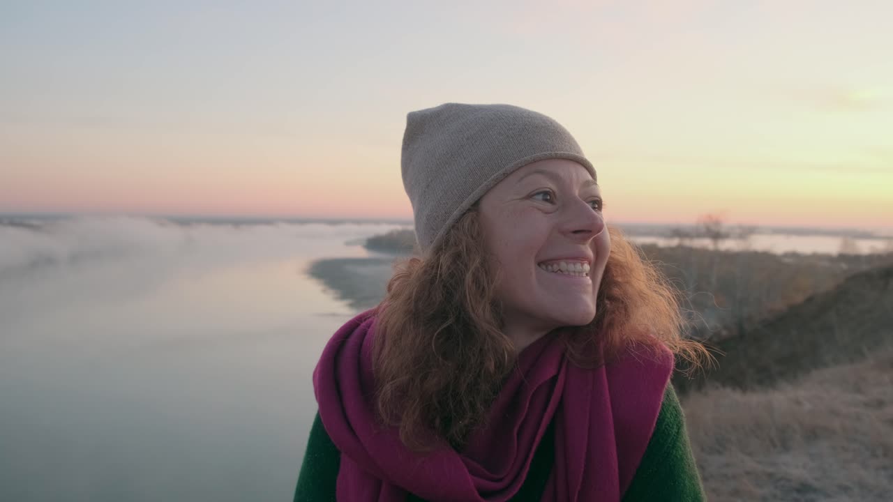 Woman enjoying a beautiful sunrise over a foggy river